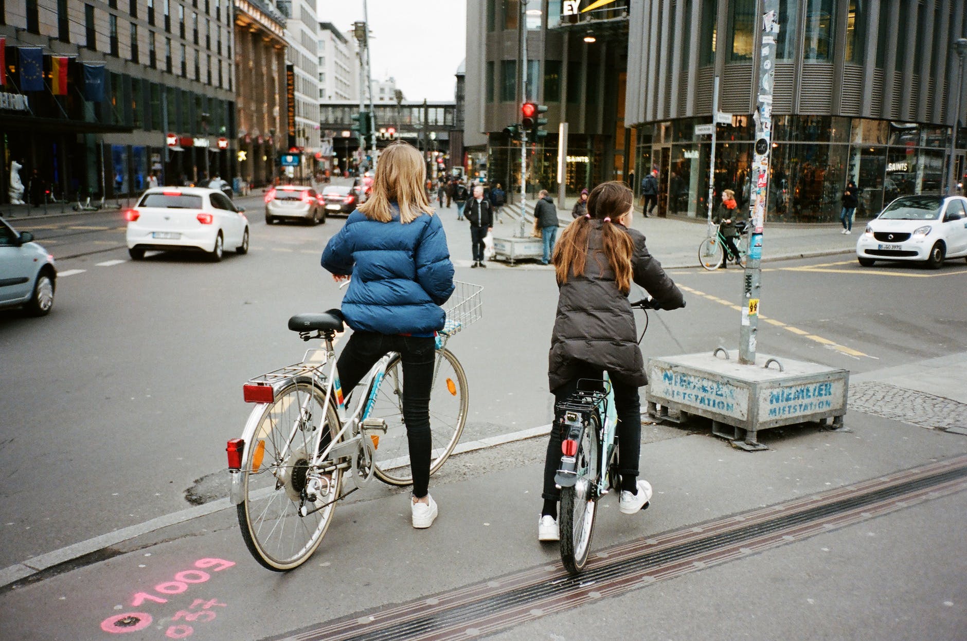 unrecognizable girlfriends riding bicycles near road in city